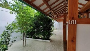 Ein überdachter Außenbereich mit Holzkonstruktion, einem Schild mit der Nummer 101 und einem kleinen Garten mit Pflanzen.