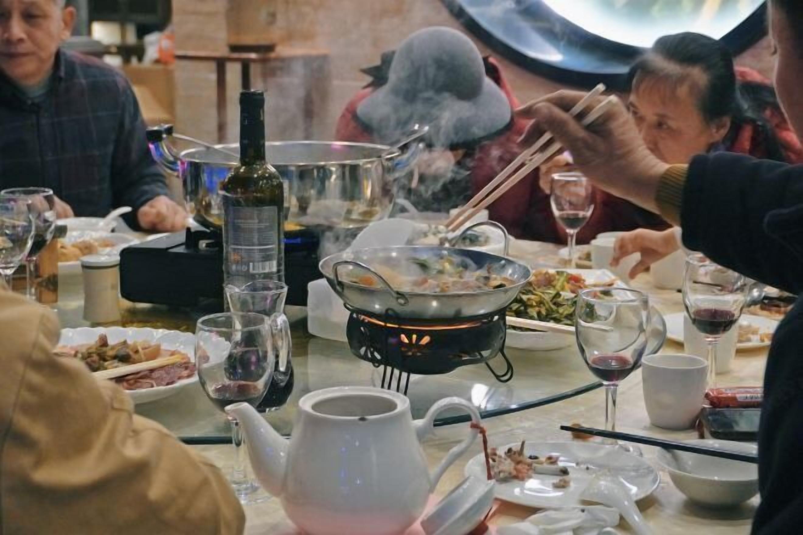 A dining table with various dishes, a teapot, and a bottle of wine.