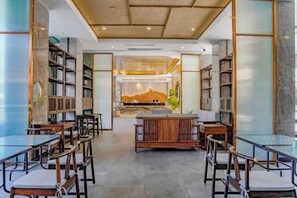 Una biblioteca amplia con estanterías, mesas y sillas dispuestas para leer y comer.