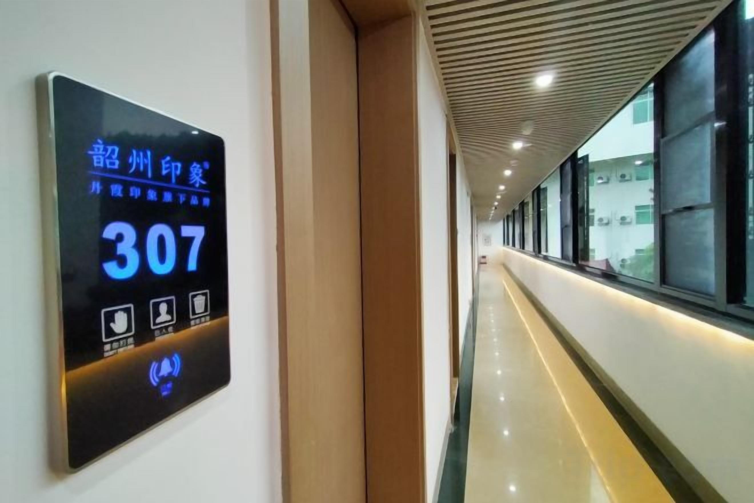 A hallway with a digital sign displaying room number 307, a ceiling with a wooden pattern, and a window on the right.