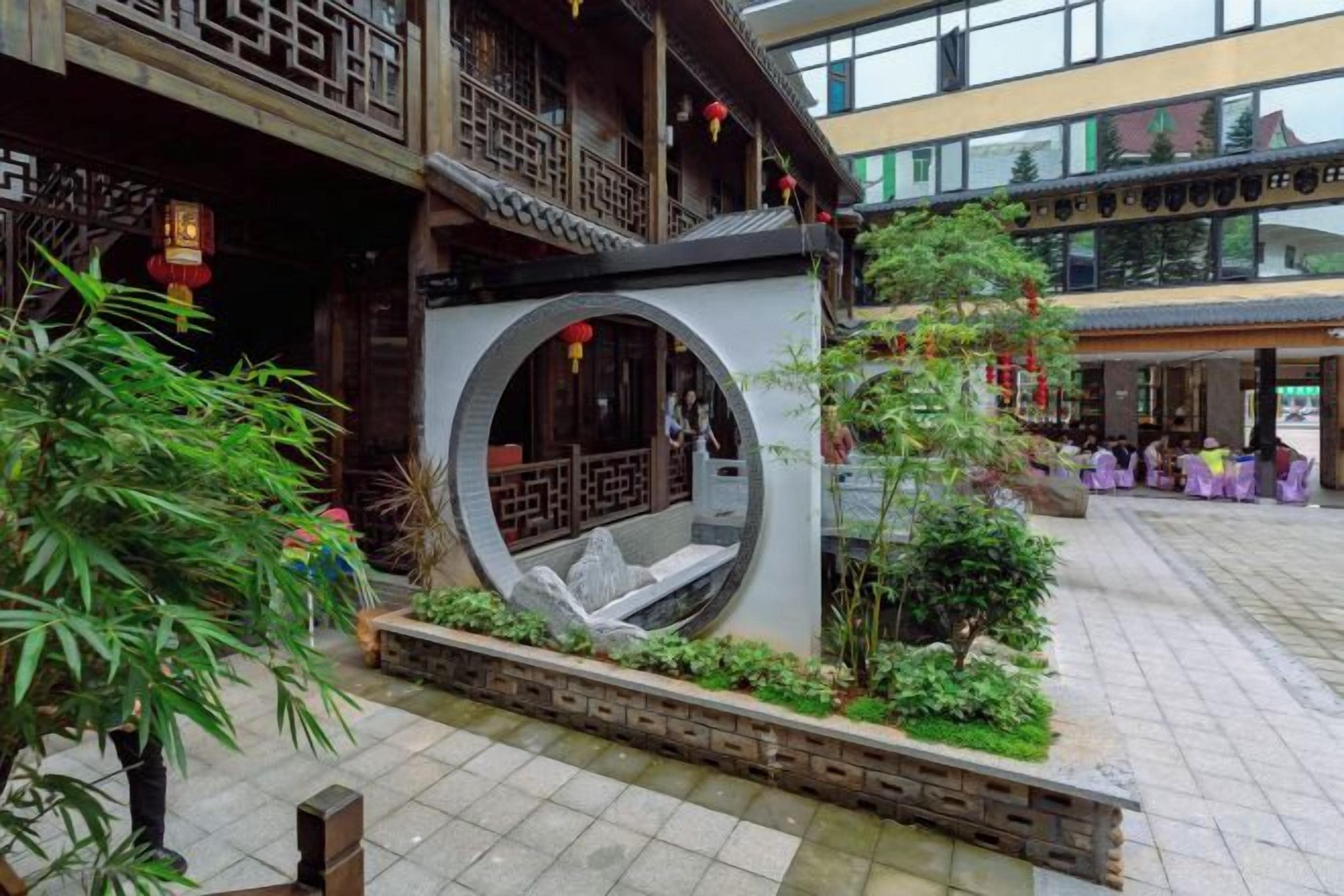 A courtyard with a traditional Chinese architectural design, including a circular stone structure and a wooden balcony.