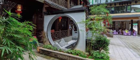 A courtyard with a traditional Chinese architectural design, including a circular stone structure and a wooden balcony.