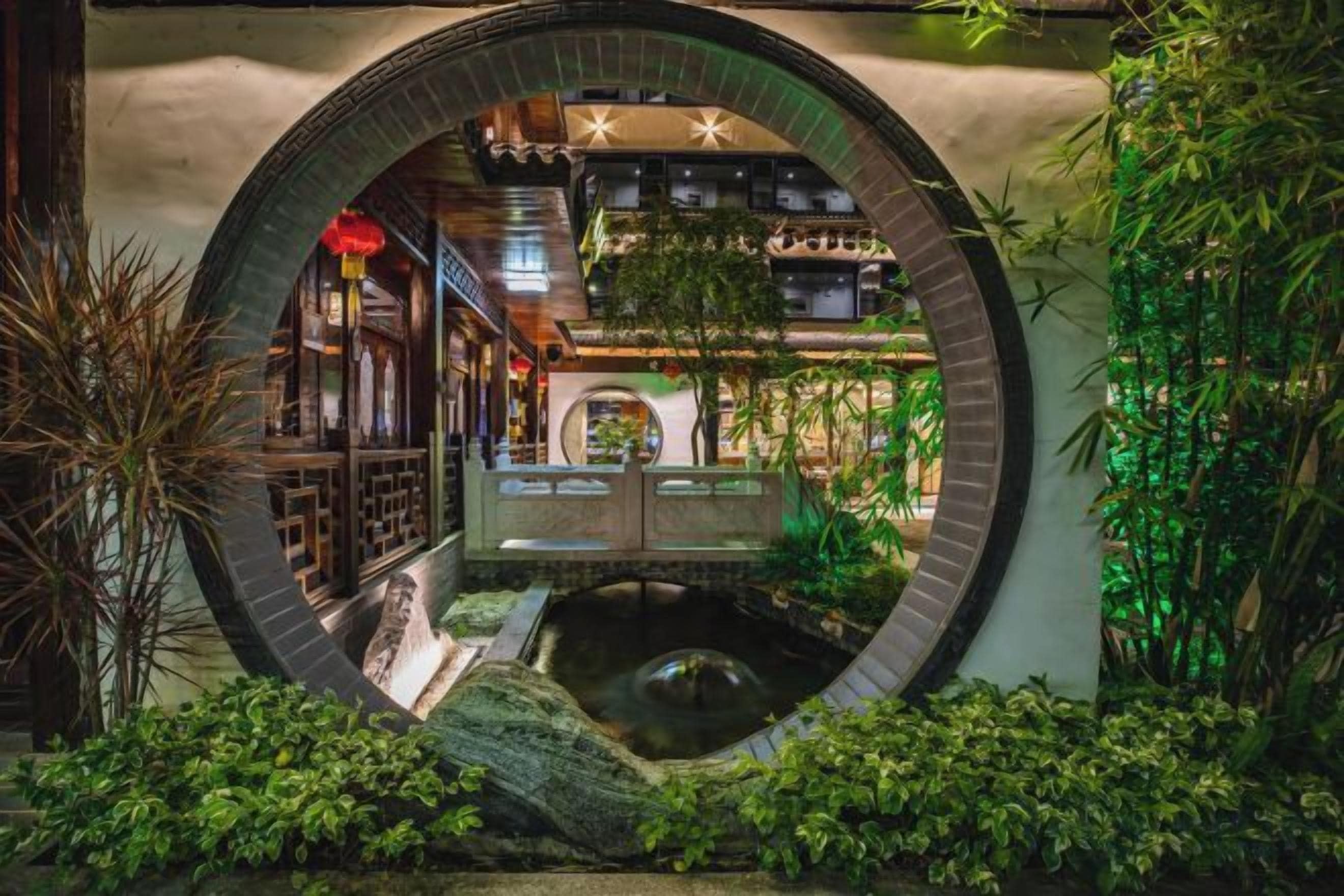 A circular architectural feature with a water body and greenery, surrounded by traditional-style buildings.