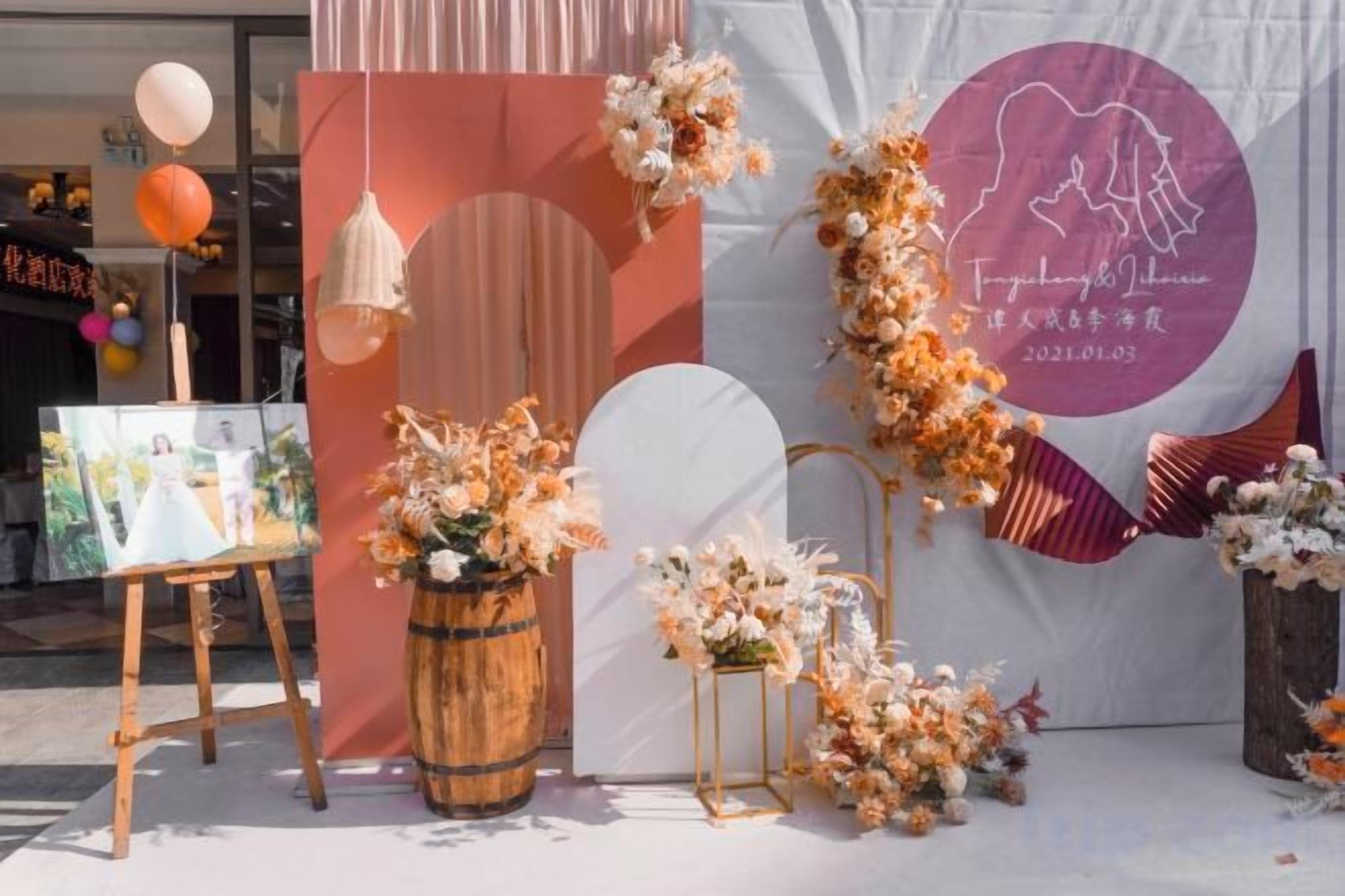 A decorated event space with a stage, floral arrangements, and a backdrop with text.