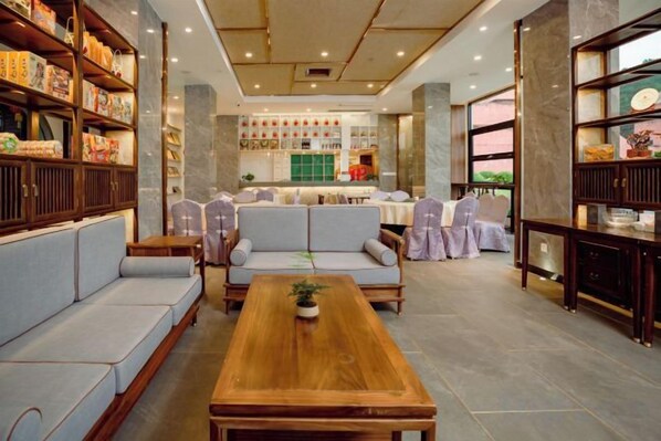 A hotel lobby with a wooden reception desk, sofas, and a dining area. - Renhua Shaozhou Impression Boutique Cultural Hotel (Renhua)