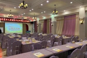 A conference room with rows of tables and chairs, a projection screen, and a banner with text. - Renhua Shaozhou Impression Boutique Cultural Hotel (Renhua)