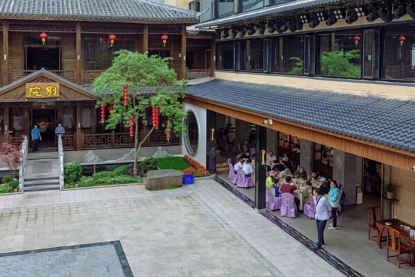 A courtyard with a traditional building, a tree, and a group of people gathered outside. - Renhua Shaozhou Impression Boutique Cultural Hotel (Renhua)