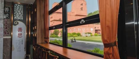 Interior de un restaurante con una larga barra de madera, sillas y vista a un edificio.