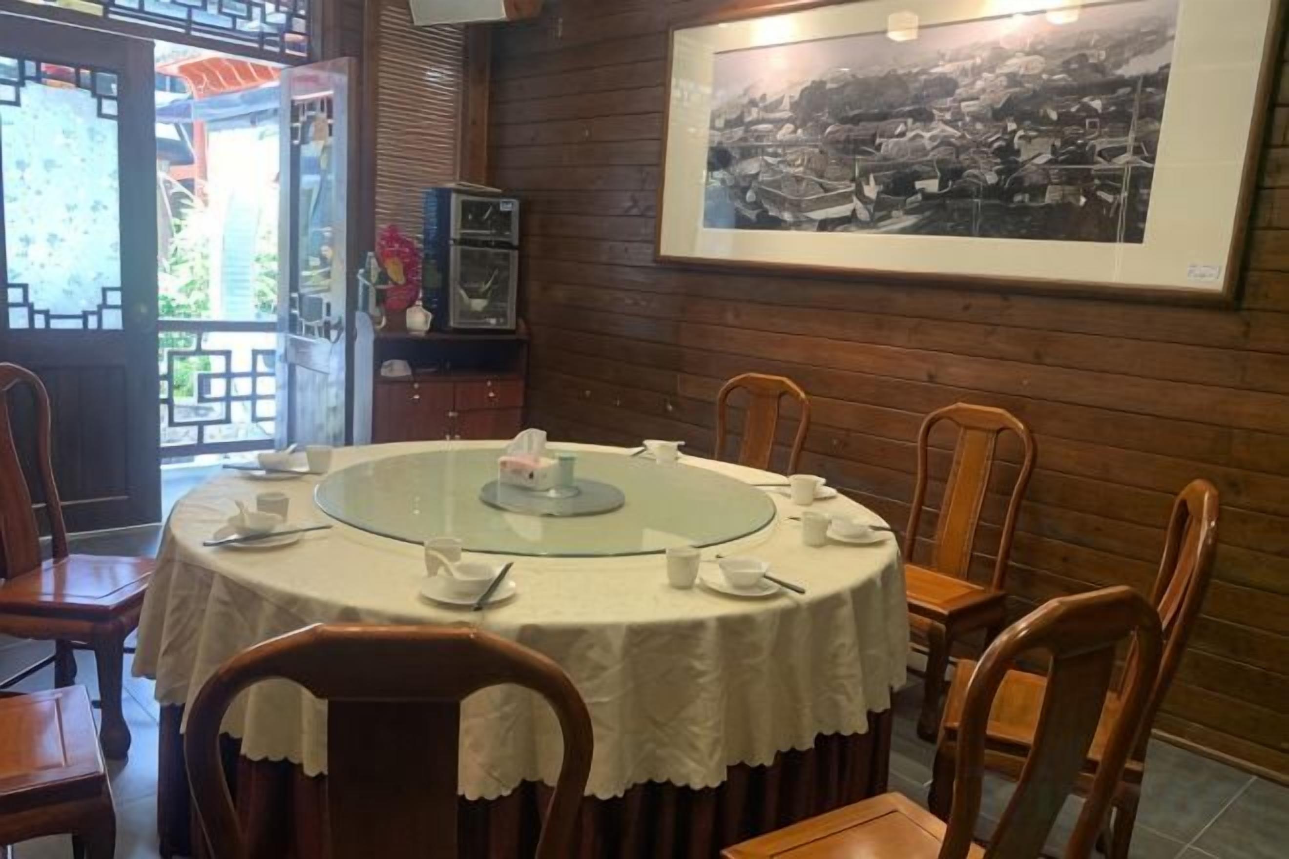 A round table with chairs, a framed picture on the wall, and a view through an open door.