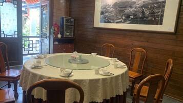 A round table with chairs, a framed picture on the wall, and a view through an open door.