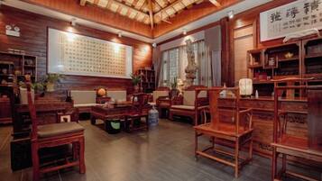 Habitación de estilo tradicional con muebles de madera, una pared con caligrafía y un techo con vigas a la vista.