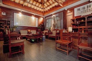 A traditional-style room with wooden furniture, a large wall with calligraphy, and a ceiling with exposed beams. - Renhua Shaozhou Impression Boutique Cultural Hotel (Renhua)
