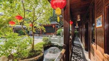 A traditional wooden building with a courtyard, a small water feature, and red lanterns.
