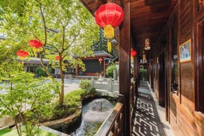 Un edificio tradicional de madera con un patio, una fuente pequeña y faroles rojos.