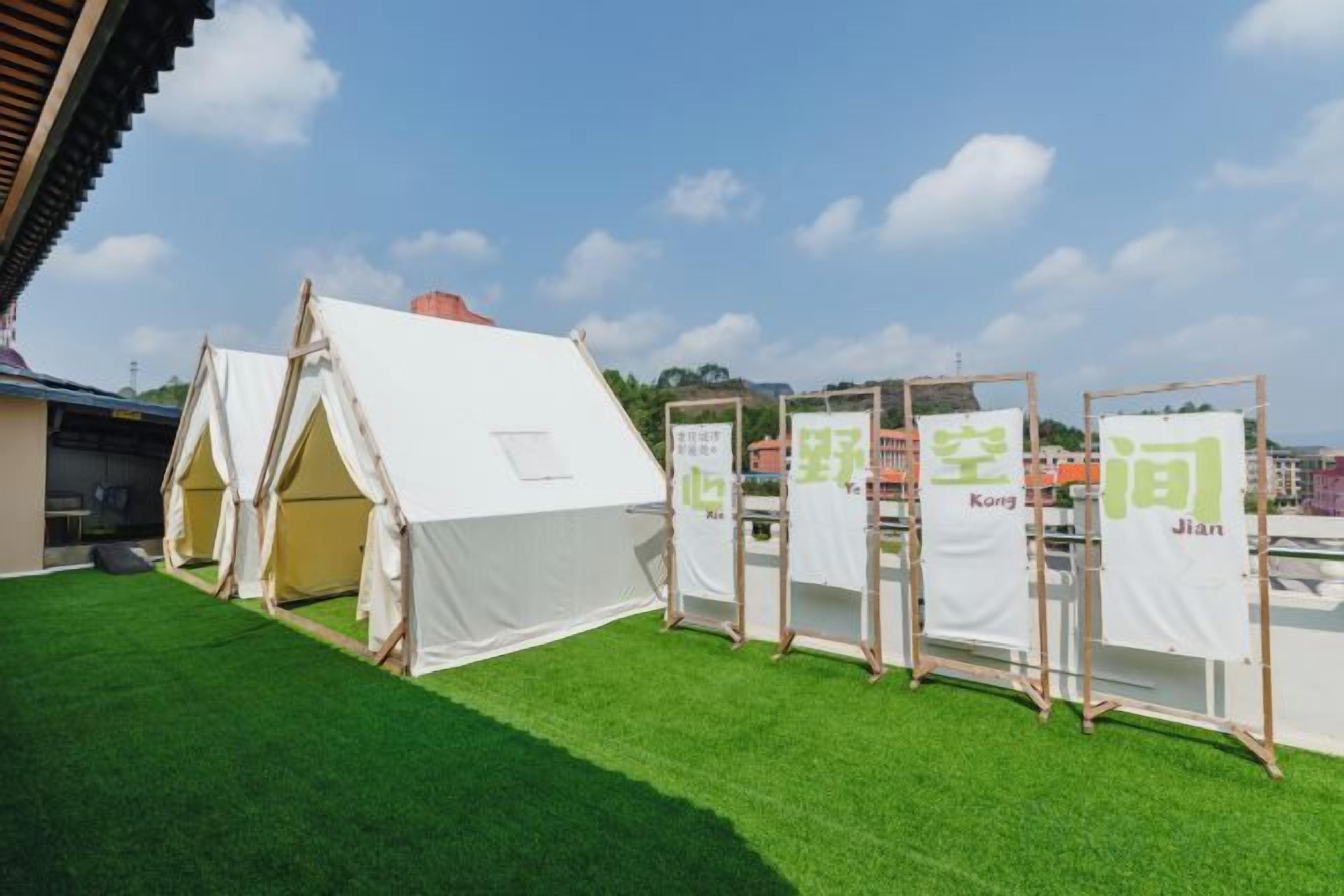 A row of white tents on a green surface with banners displaying Chinese characters.