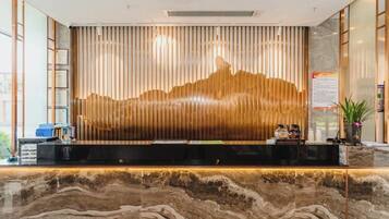 A reception desk with a marble countertop, vertical wooden slats, and a cityscape mural.
