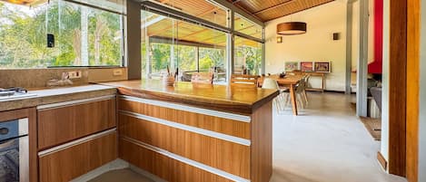 A modern kitchen with wooden cabinetry, a large island, and a view of the outdoors.