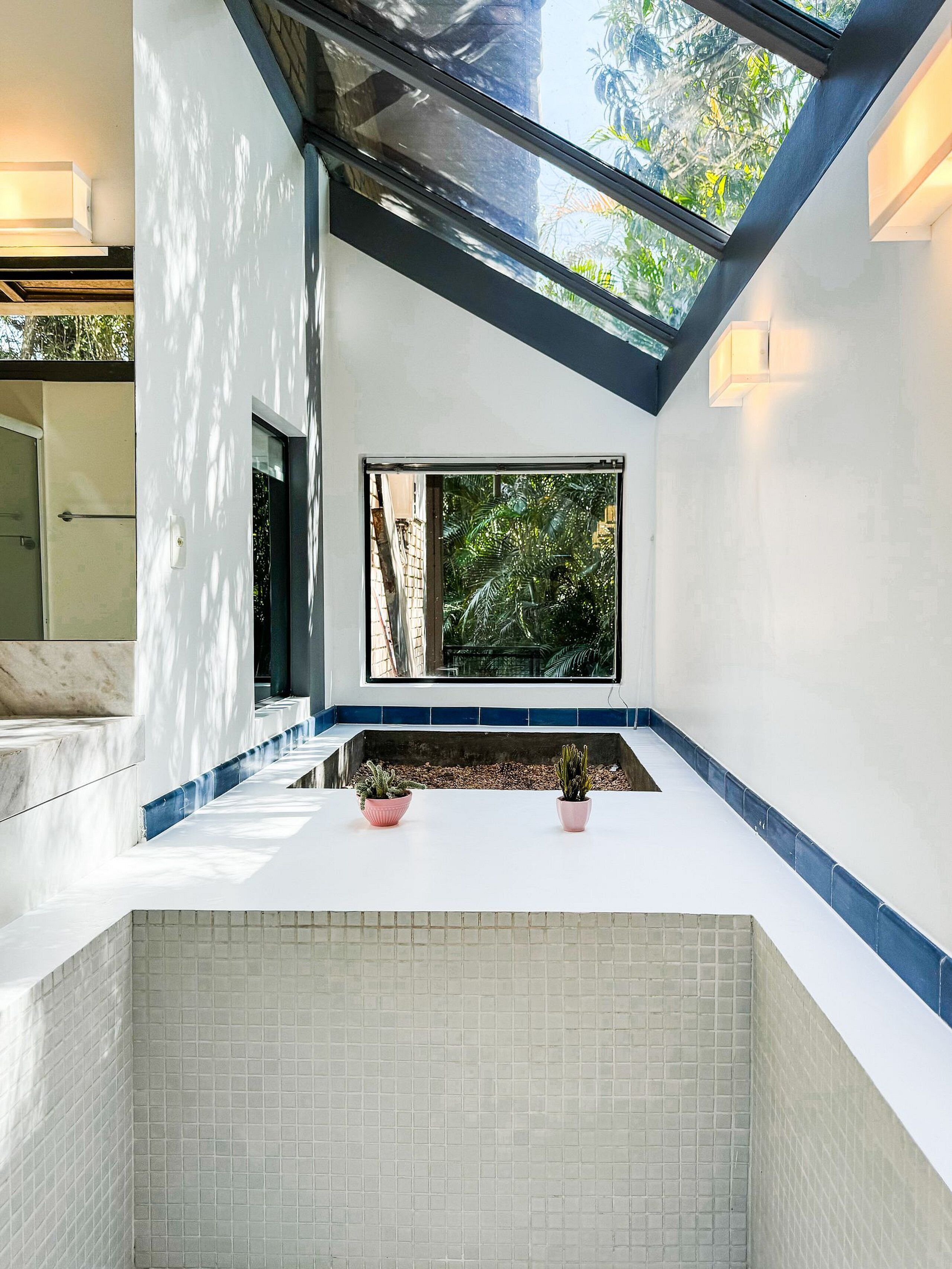 A modern interior with a skylight, white walls, and a tiled floor.