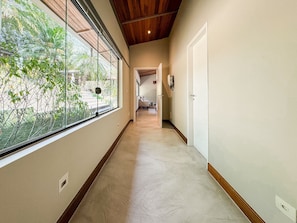 A hallway with a large window, wooden ceiling, and a door at the end. - Casa térrea com piscina e cozinha de cinema | Granja Viana (Jandira)