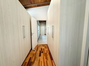 Un pasillo con suelo de madera y paredes blancas que conduce a una habitación con ventana.