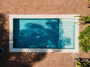 An aerial view of a rectangular swimming pool with a tiled deck, surrounded by a brick wall. - Casa térrea com piscina e cozinha de cinema | Granja Viana (Jandira)