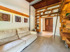 A modern living room with a beige sofa, wooden shelves, and framed artwork on the wall. - Casa térrea com piscina e cozinha de cinema | Granja Viana (Jandira)