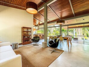 Un amplio salón con un ventanal grande, techo de madera y un comedor con sillas y una mesa.