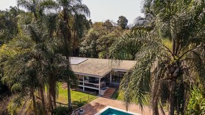 A house with a swimming pool surrounded by lush greenery. - Casa térrea com piscina e cozinha de cinema | Granja Viana (Jandira)