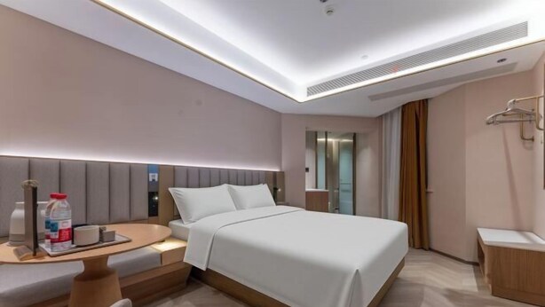 A modern hotel room with a bed, bedside table, chair, and a small desk with a lamp. - Starway Hotel (Linhai Intime City) (Linhai)