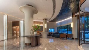 A modern lobby with a curved ceiling, a reception desk, seating area, and large windows. - Starway Hotel (Linhai Intime City) (Linhai)