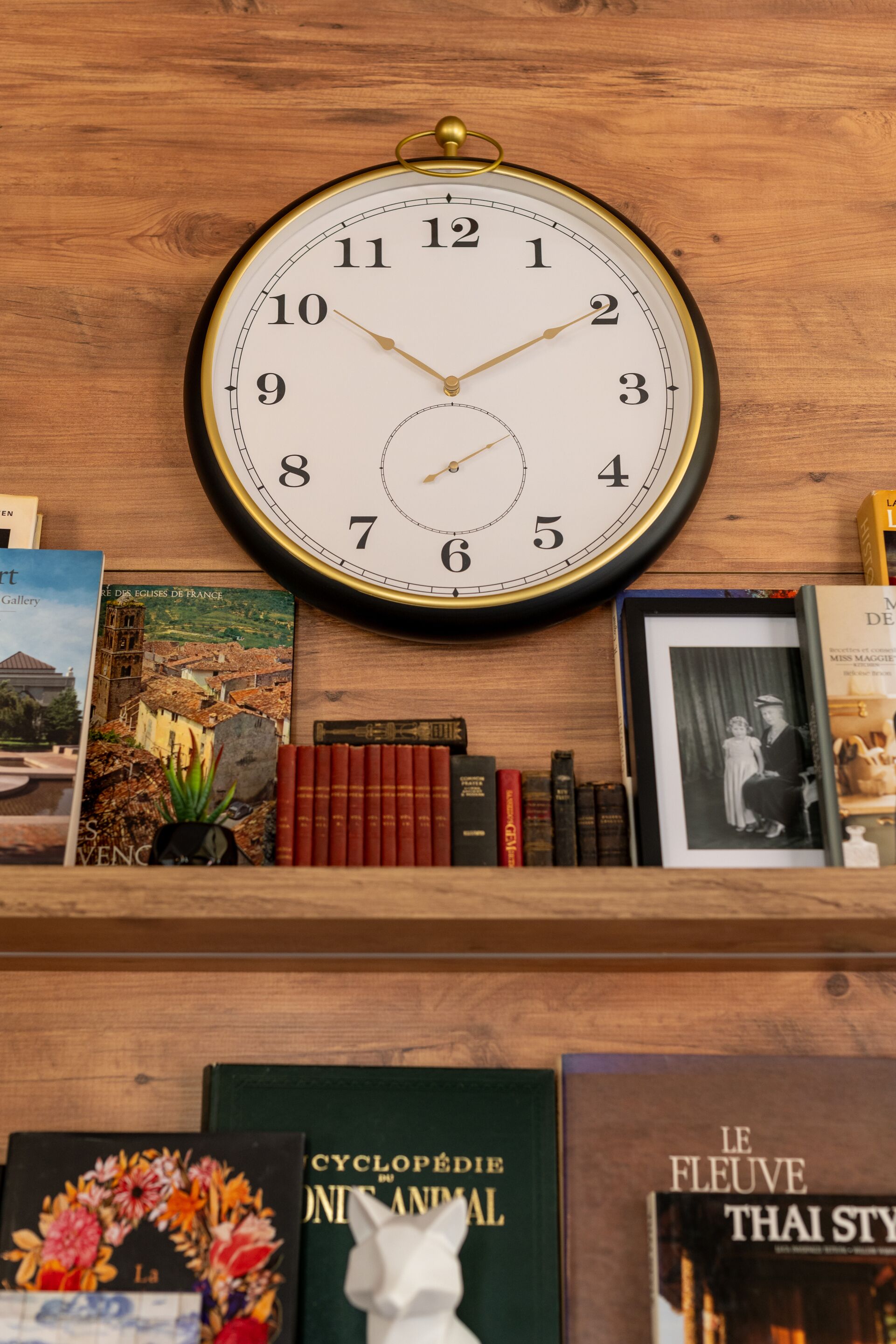 Une horloge murale ronde, dotée d’un cadre doré, fixée à un mur en bois.