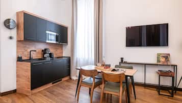 Una cocina moderna con armarios negros, una encimera de madera y una cafetera. Hay una mesa de comedor con sillas y una mesita auxiliar con un tocadiscos.