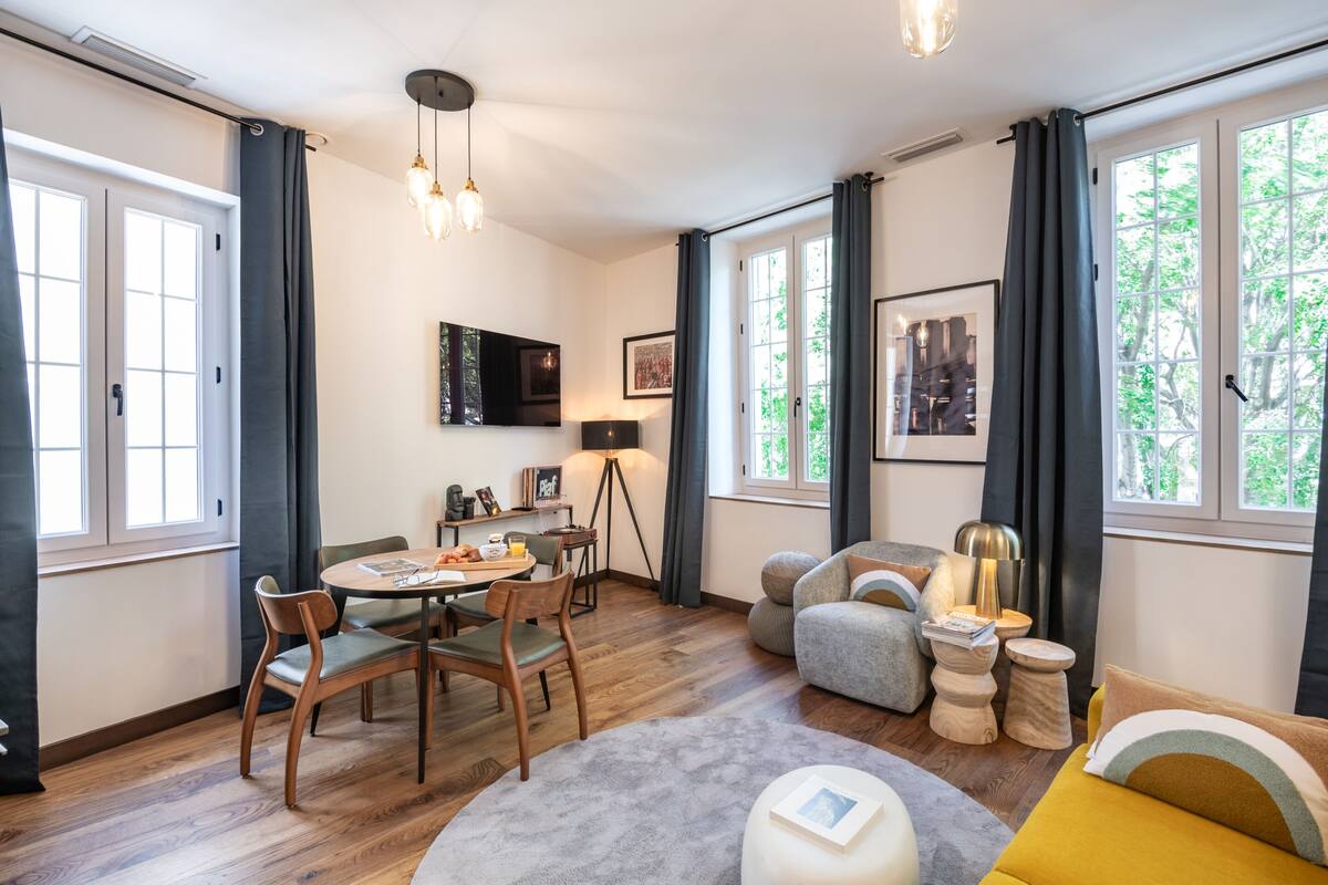 A modern living room with a dining area, large windows, and a cozy seating arrangement.