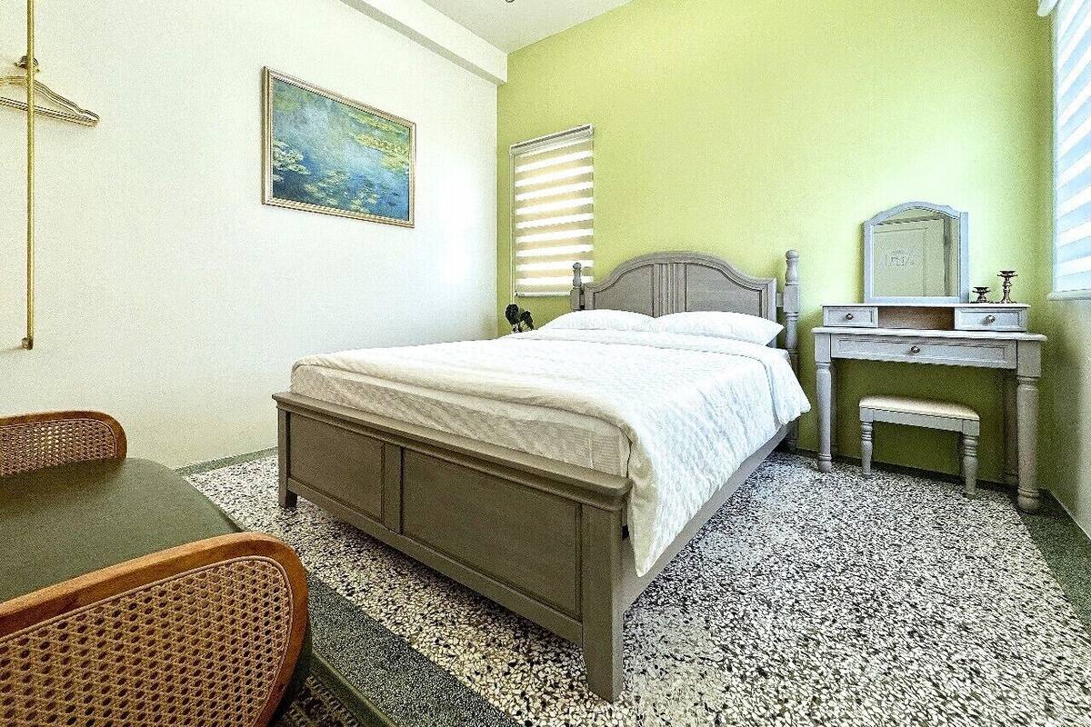 A bedroom with a bed, a dresser, a chair, and a painting on the wall.