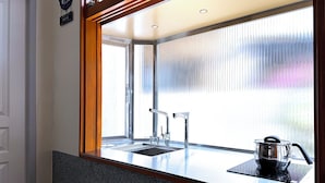 A kitchen with a stainless steel sink, a modern faucet, and a pot on a black induction cooktop. - Ronchamp Villa (Tainan)