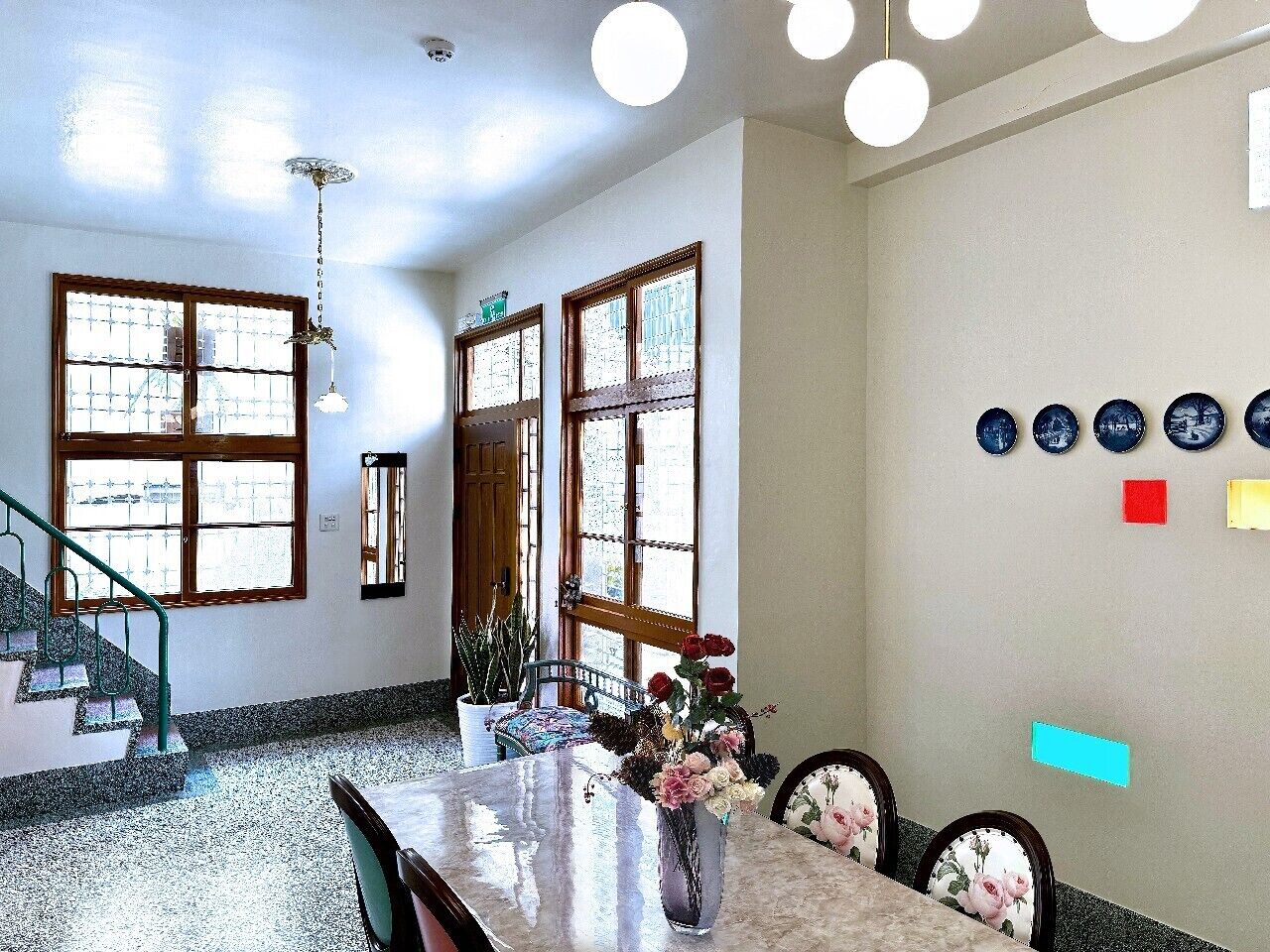A dining area with a marble table, chairs, a vase of flowers, and a staircase leading to another room.