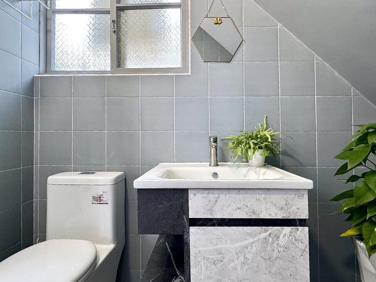 Une salle de bain avec des toilettes, un lavabo et une fenêtre.