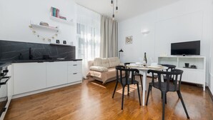 Cuina moderna amb armaris blancs, tauleig negre i zona de menjador amb taula i cadires.