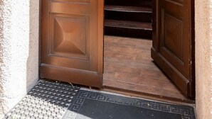 Una porta doble de fusta que dona a una escala amb una paret de maó i una porta de fusta al fons.