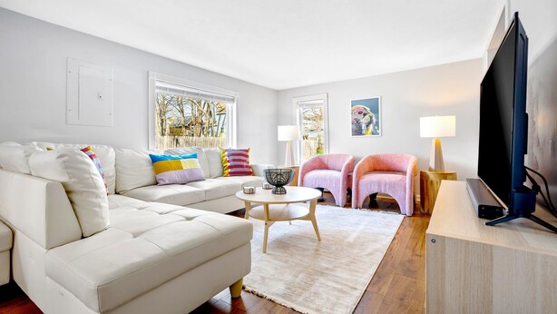 A modern living room with a white sofa, a round coffee table, and a flat-screen TV on a wooden stand. - Walk to beach, shuffleboard, and bunk room (Old Orchard Beach)
