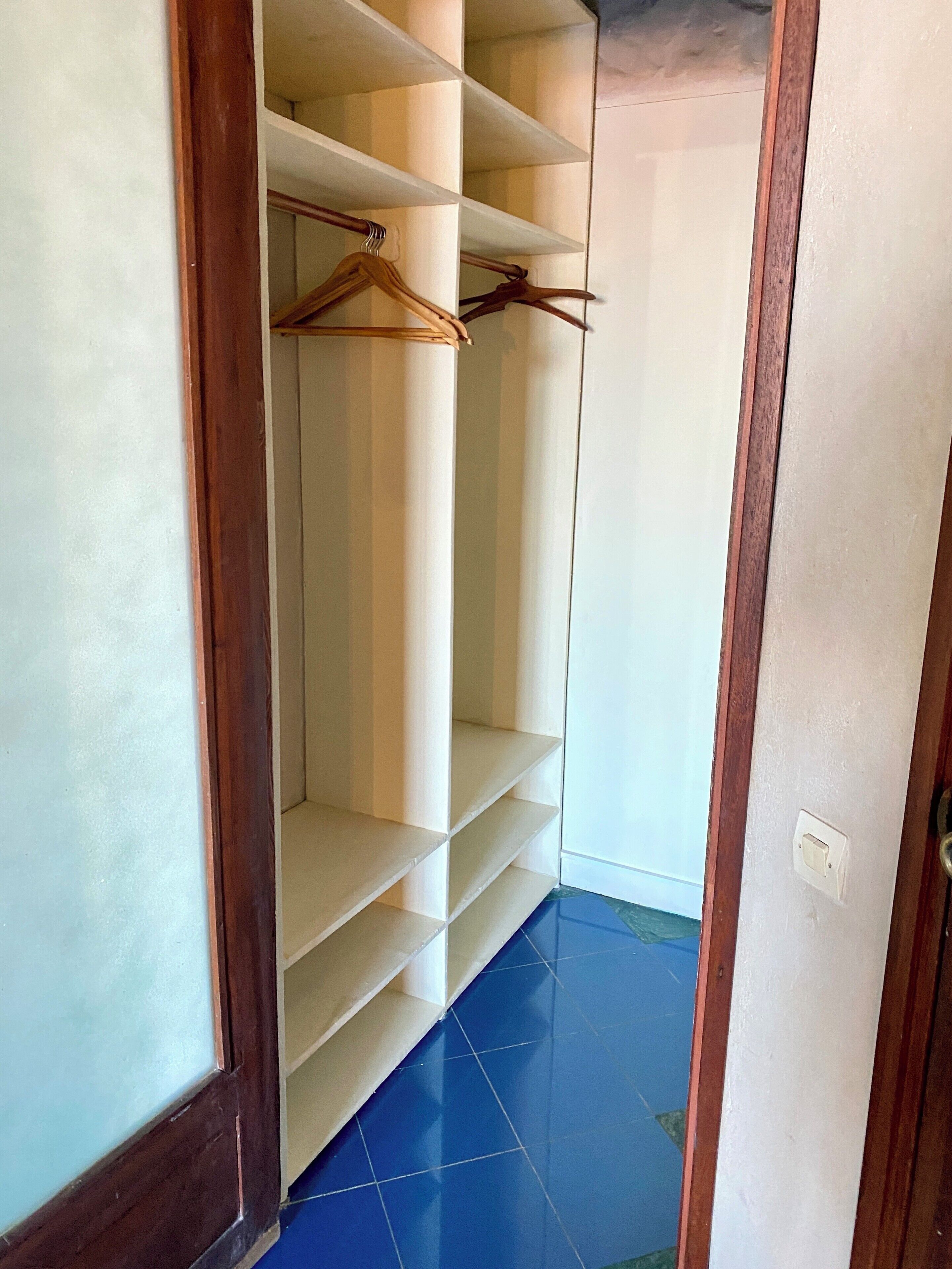 Un armario de vestidor con múltiples estantes y espacio para colgar.