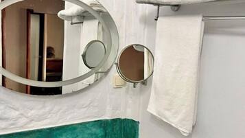 Un baño con un lavamanos blanco, dos espejos y un perchero para toallas.