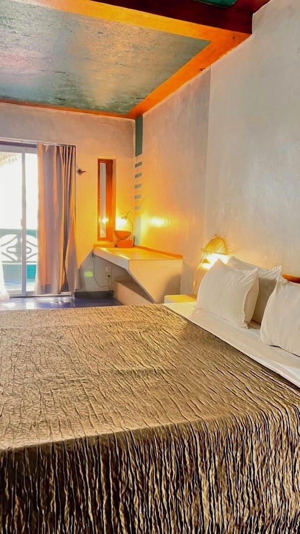 A hotel room with a bed, a desk, and a view of the outside. - Sokhamon (Dakar)