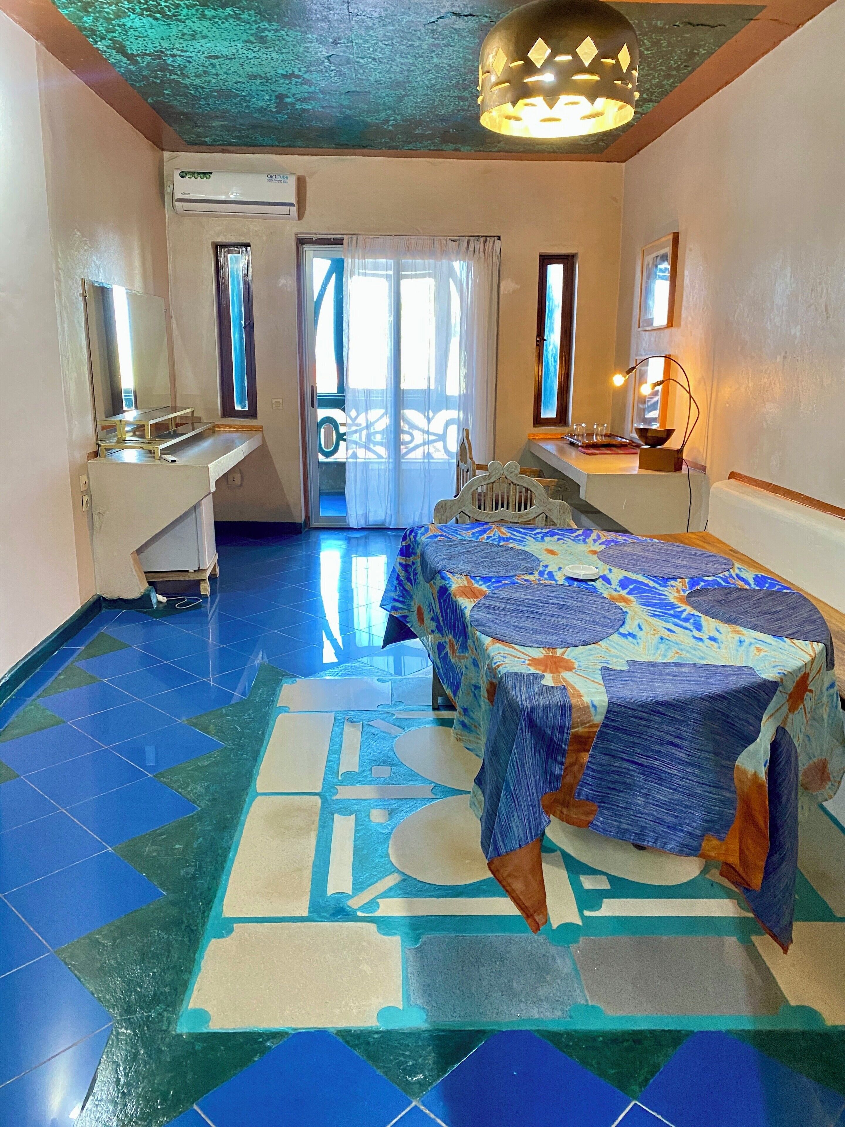 Una habitación de hotel con cama, escritorio, aire acondicionado y vista a través de una puerta.