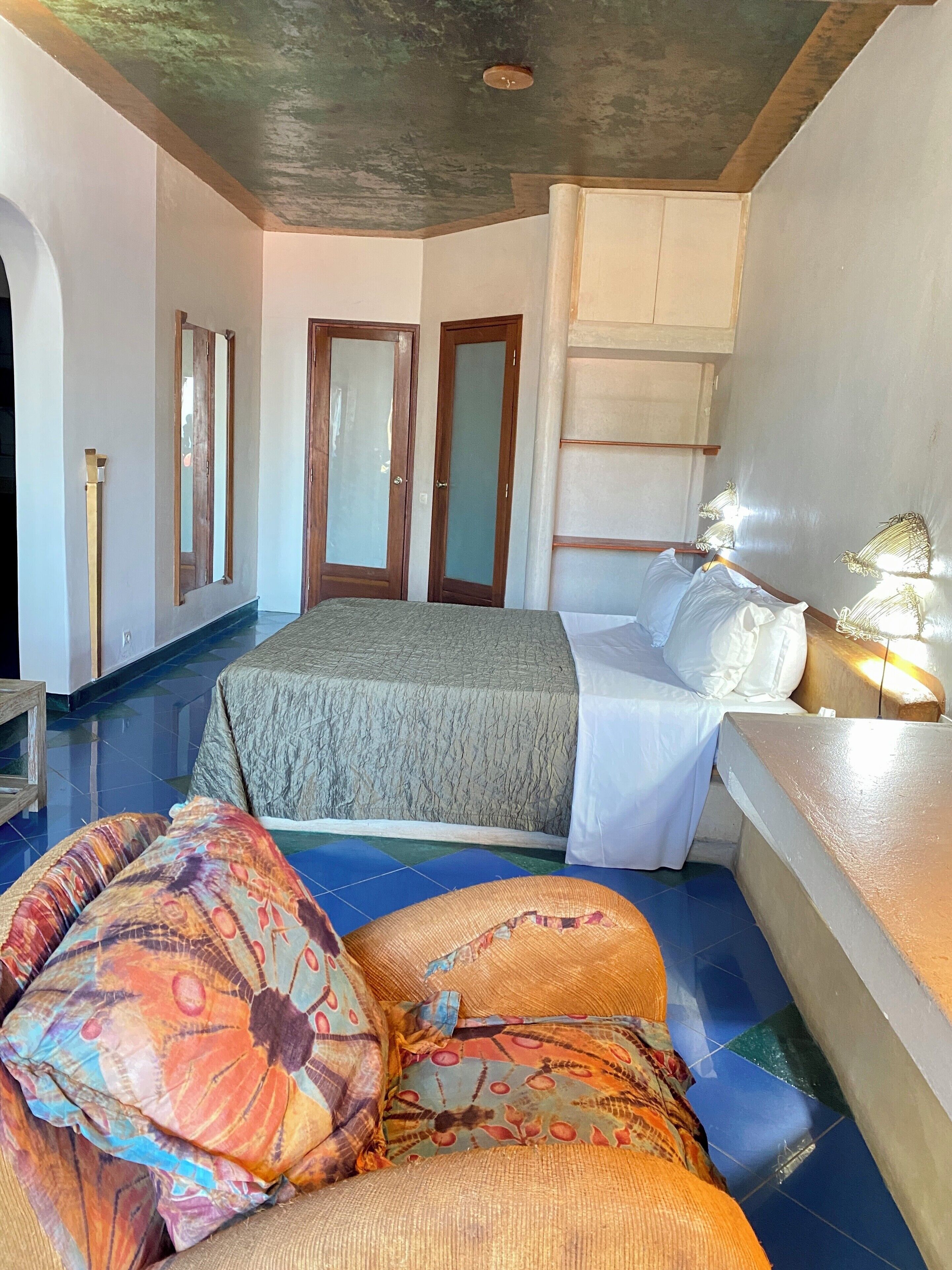 Un dormitorio con cama, almohadas, mesita de noche y espejo.
