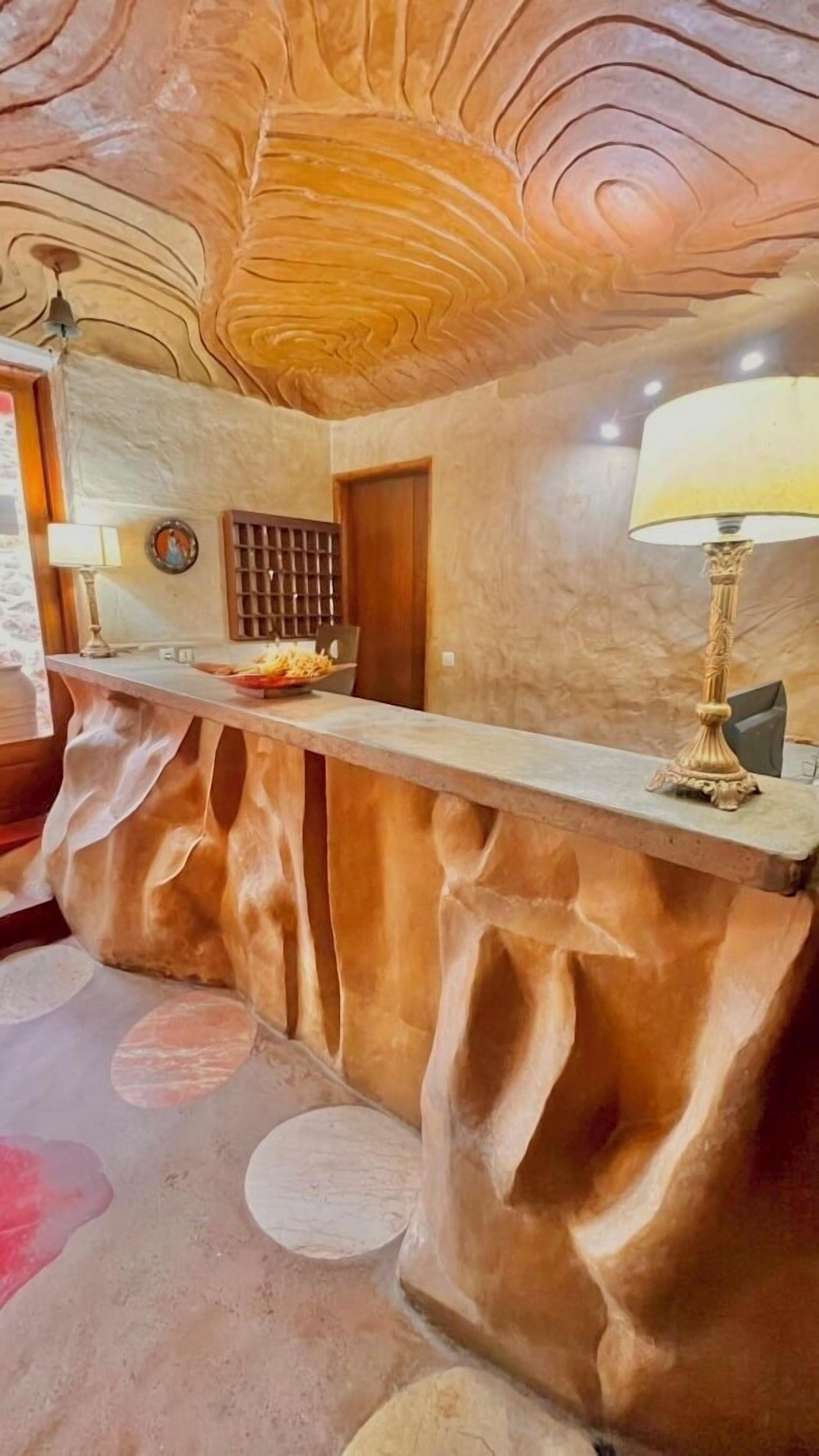 A reception desk with a unique wavy design, a wooden door, and a lamp.