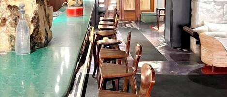 Un área de bar con taburetes de madera, una barra verde y una pared de piedra.