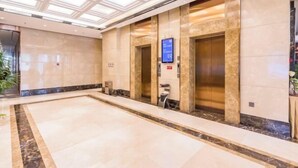 Eine großzügige Lobby mit Marmorböden, einer zentralen Säule und zwei Aufzügen.