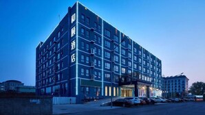 Ein mehrstöckiges Hotel im modernen Stil, mit einem markanten Eingang und einem Parkplatz davor.