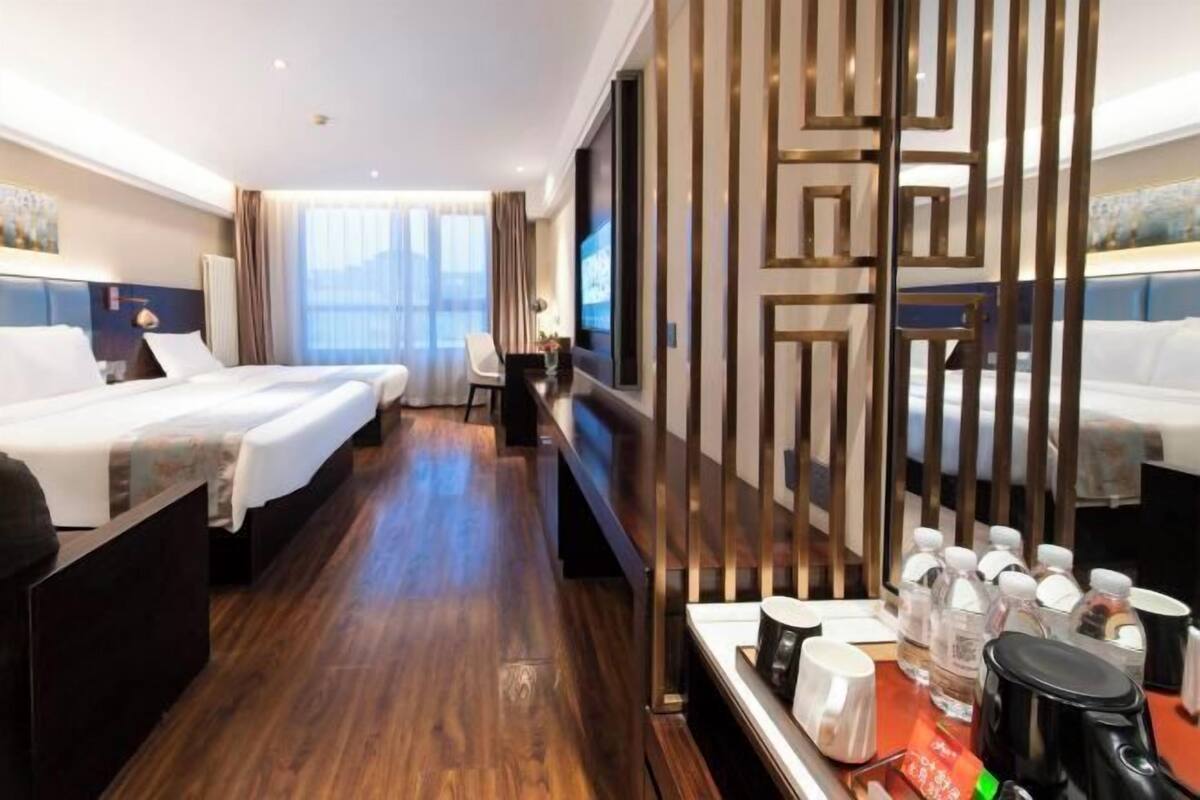 A hotel room with two beds, a desk with a coffee maker, and a TV.